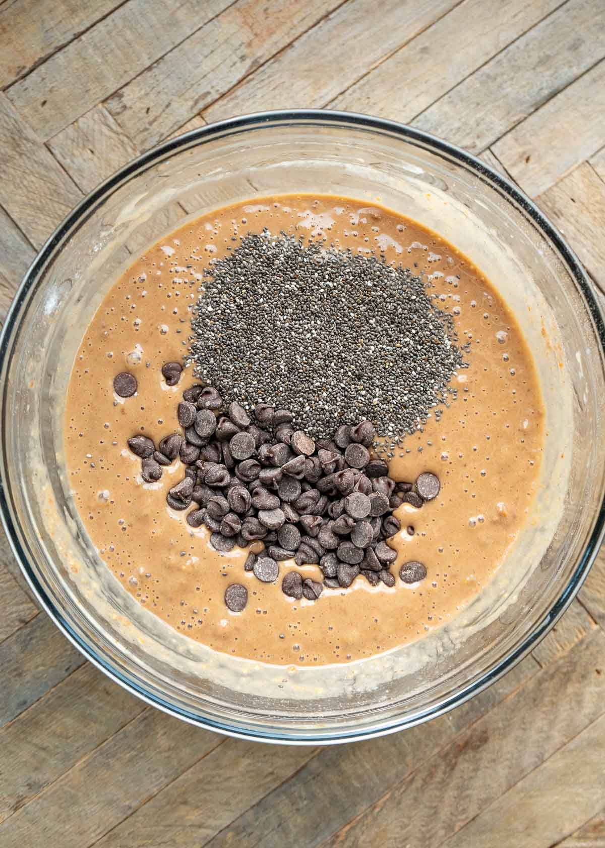 chia seeds and chocolate chips added into a flourless waffle batter in a glass bowl