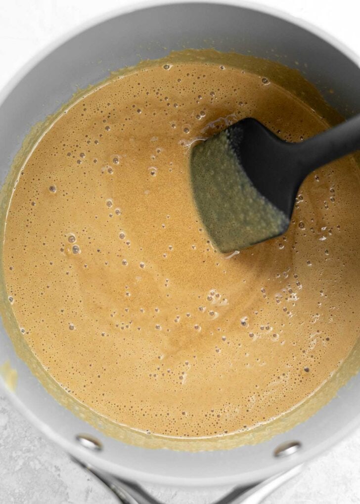 coconut oil and peanut butter melting in a sauce pan with a silicone spatula