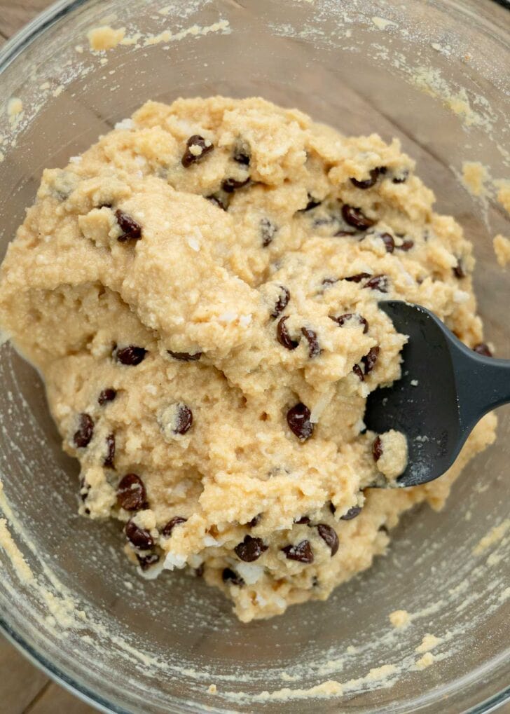 silicone spatula folding in chocolate chips and coconut flakes for low-carb muffins