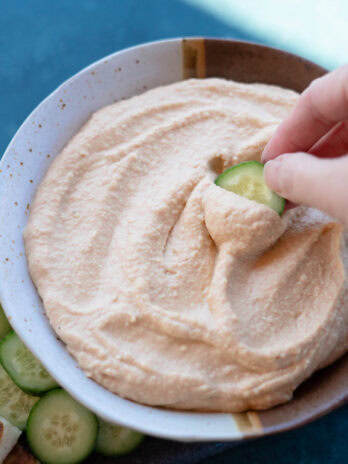 a closeup shot of ultra creamy feta hummus being spread onto a cucumber slice