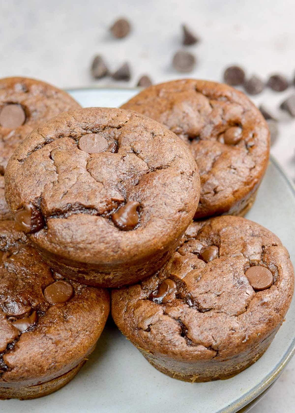 side angle showing fluffy gluten-free muffins on a plate packed with chocolate chips