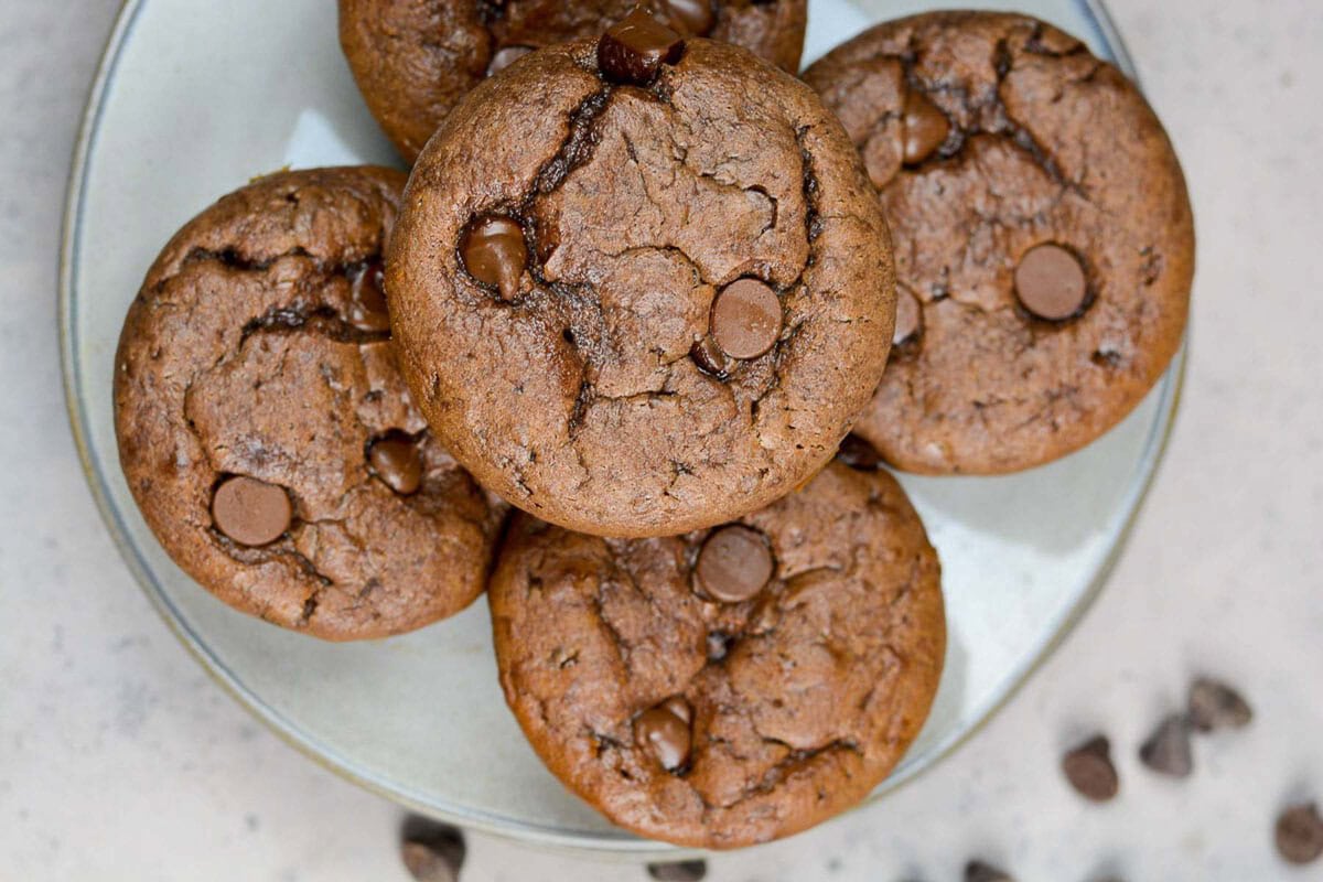 Horizontal image; overhead view of chocolate protein muffins on a plate with chocolate chips