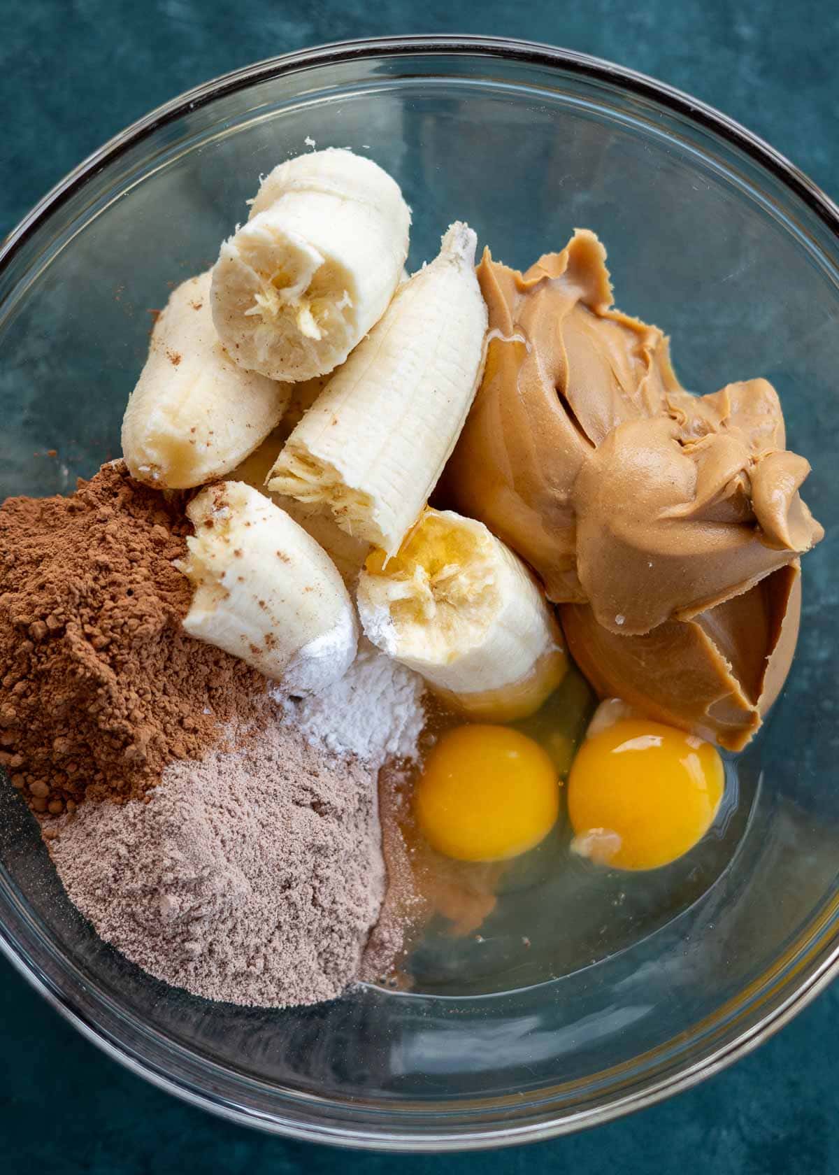 ripe bananas, creamy peanut butter, cocoa powder, protein powder, eggs, baking powder, and salt in a glass bowl