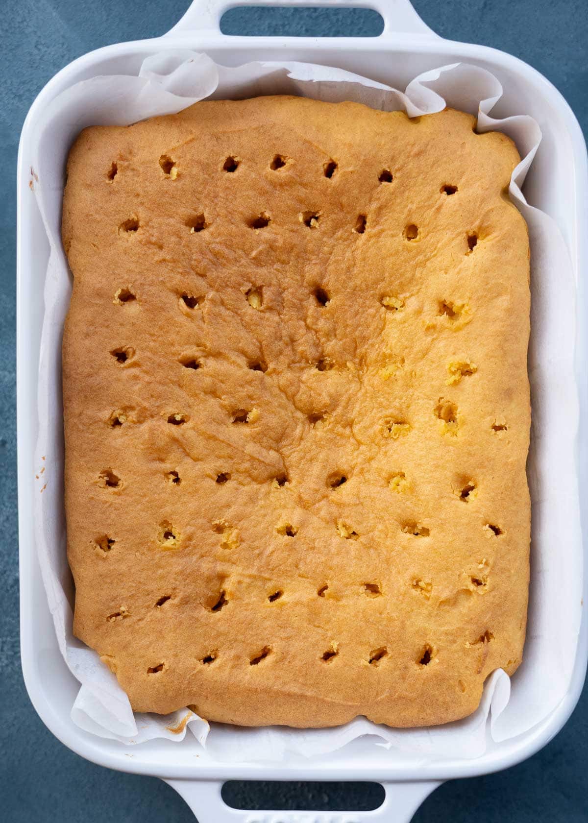 a gluten-free yellow cake baked, cooled, and then poked with holes evenly throughout in a 9x13 baking dish